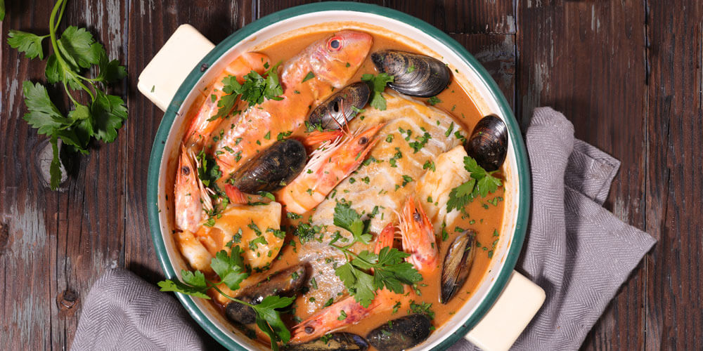 Bouillabaise mit Muscheln und Kräutern schön angerichtet in einem Kopftopf von oben betrachtet